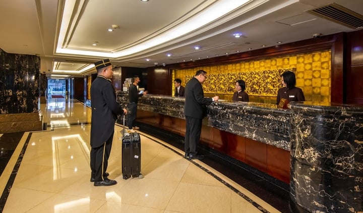a man in a suit standing at the front desk of a hotel
