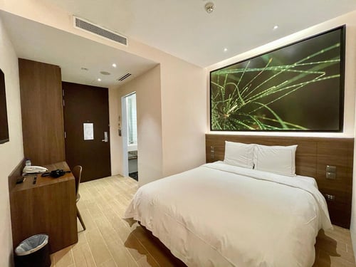 a bed in a room with a large screen on the wall