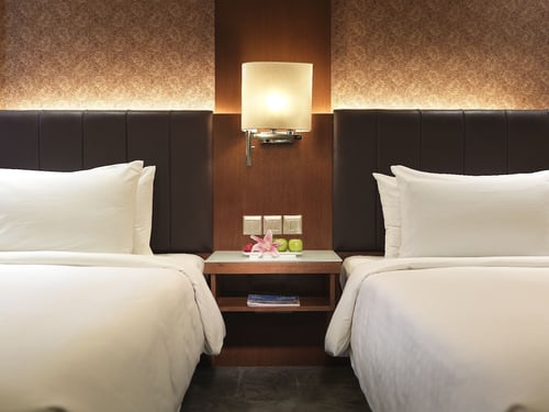dua katil di dalam bilik hotel dengan meja malam dan lampu